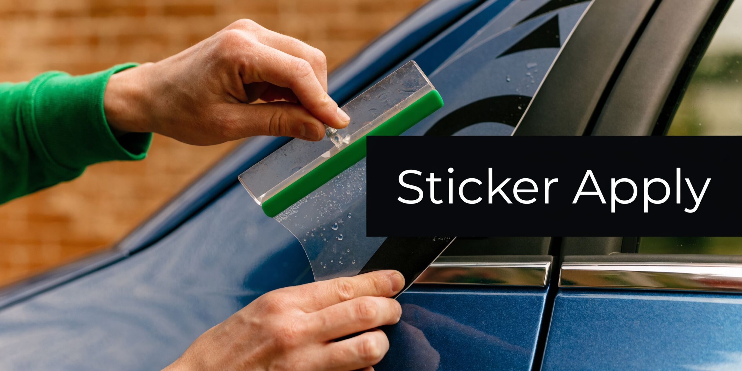 Een persoon brengt voorzichtig een vinyl sticker aan op een blauwe auto met een wisser